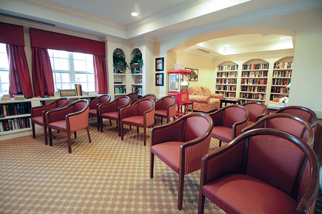 A cozy library room with rows of red chairs and bookshelves lining the walls.