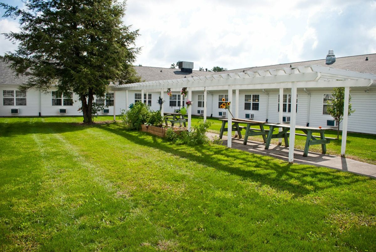 A well-maintained yard with a garden and a building in the background.