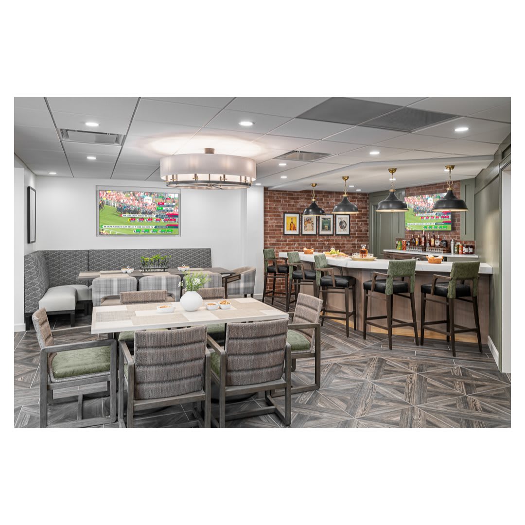 A modern kitchen and dining area with a table, chairs, and bar stools under ceiling lights.