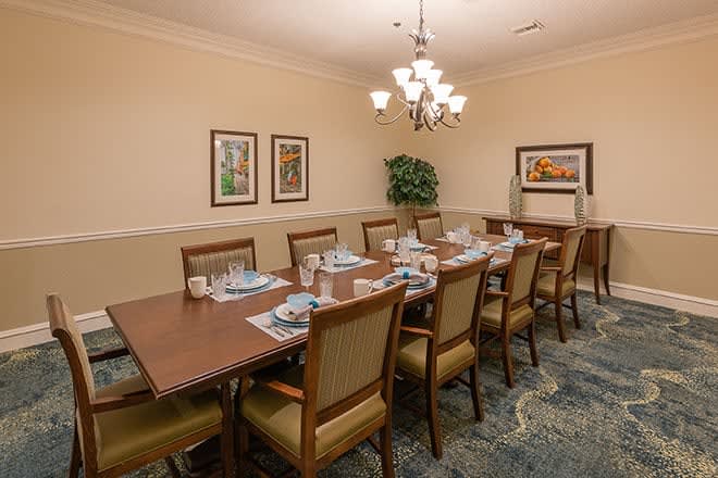 A well-appointed dining room with a long table set for a meal, surrounded by chairs and illuminated by a chandelier.