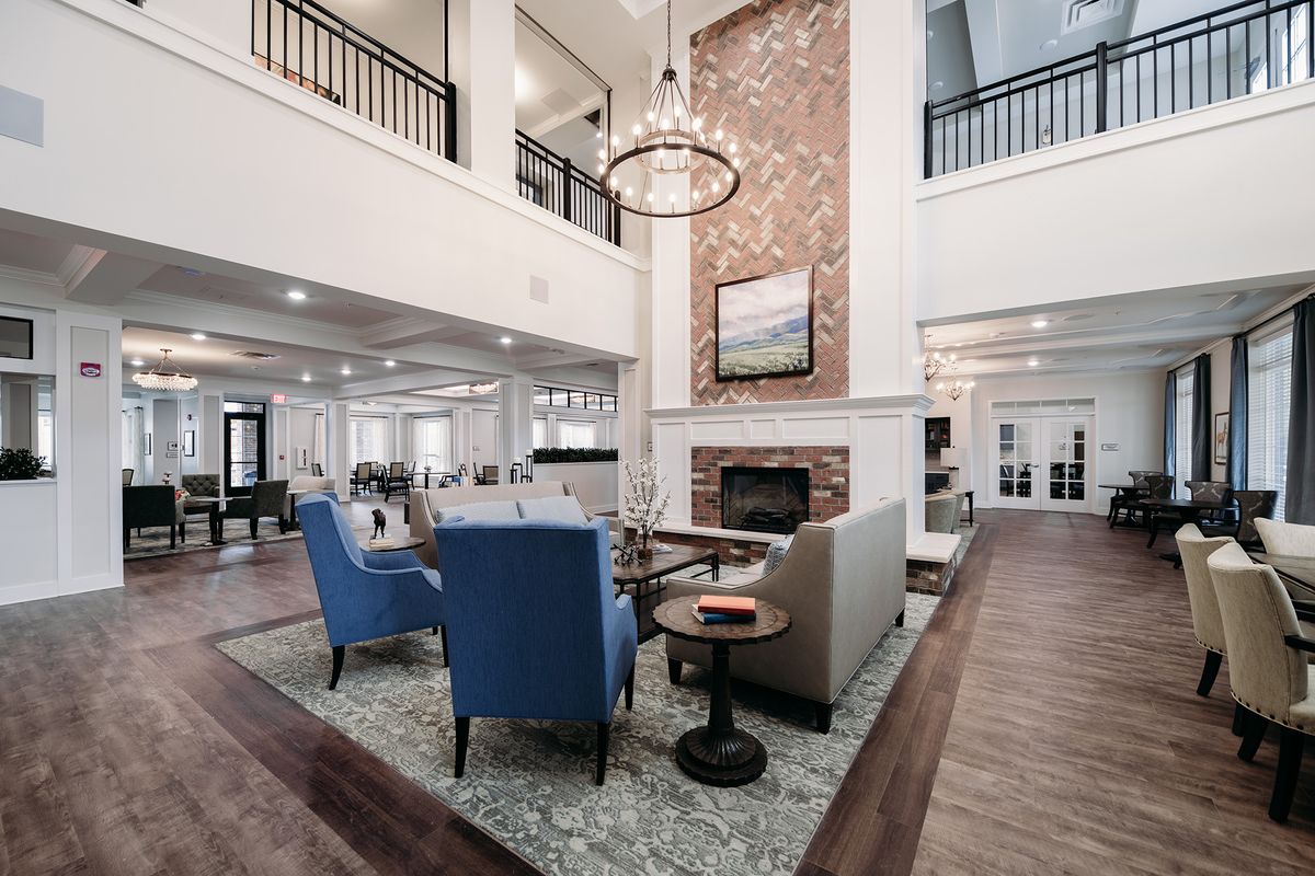 A spacious and elegantly designed living room with a fireplace, modern furniture, and a grand chandelier.