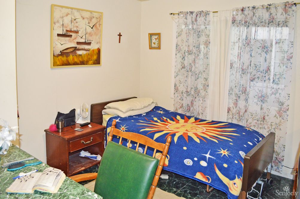 A cozy bedroom with a colorful sun-themed blanket, a wooden desk, and decorative wall art.