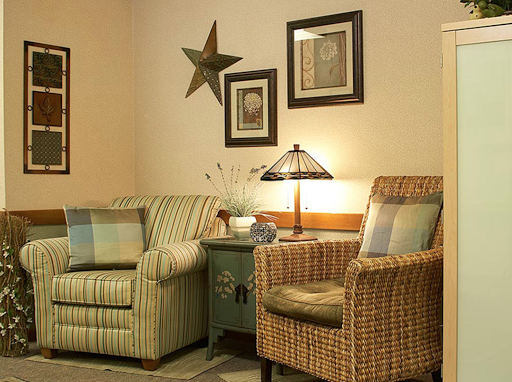 A cozy living room setup featuring two distinct chairs, a decorative lamp, and wall art.