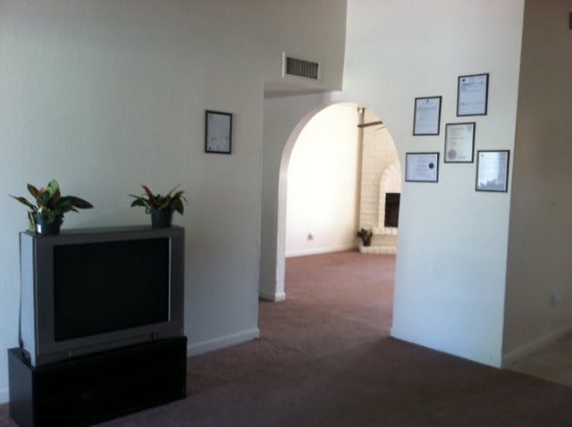 A cozy living room with a television and framed pictures on the wall.