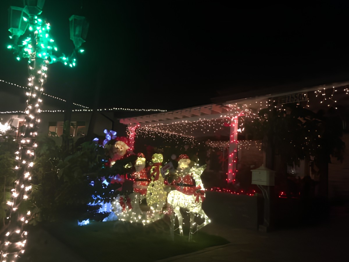 A festive outdoor display featuring illuminated Christmas decorations, including Santa Claus and reindeer at night.