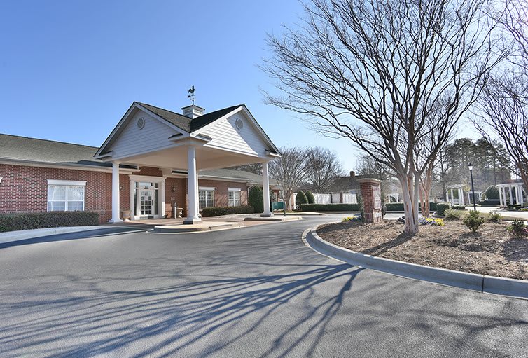 A view of a building entrance with a circular driveway surrounded by trees.