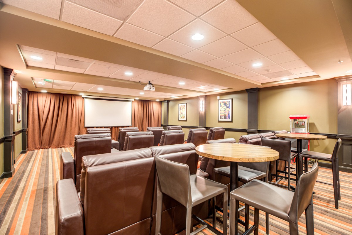 A cozy home theater room with leather seating and a projector screen.