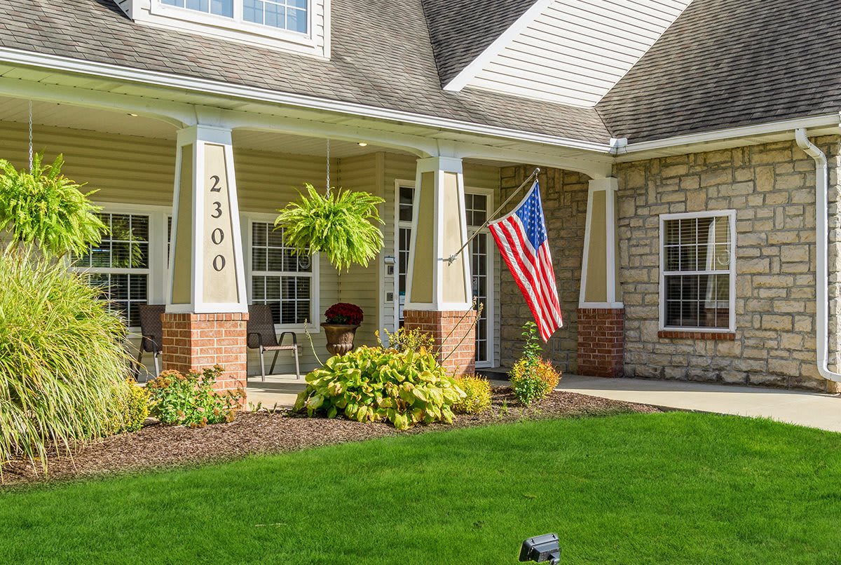 A suburban house with a well-maintained front yard and an American flag displayed on the porch.