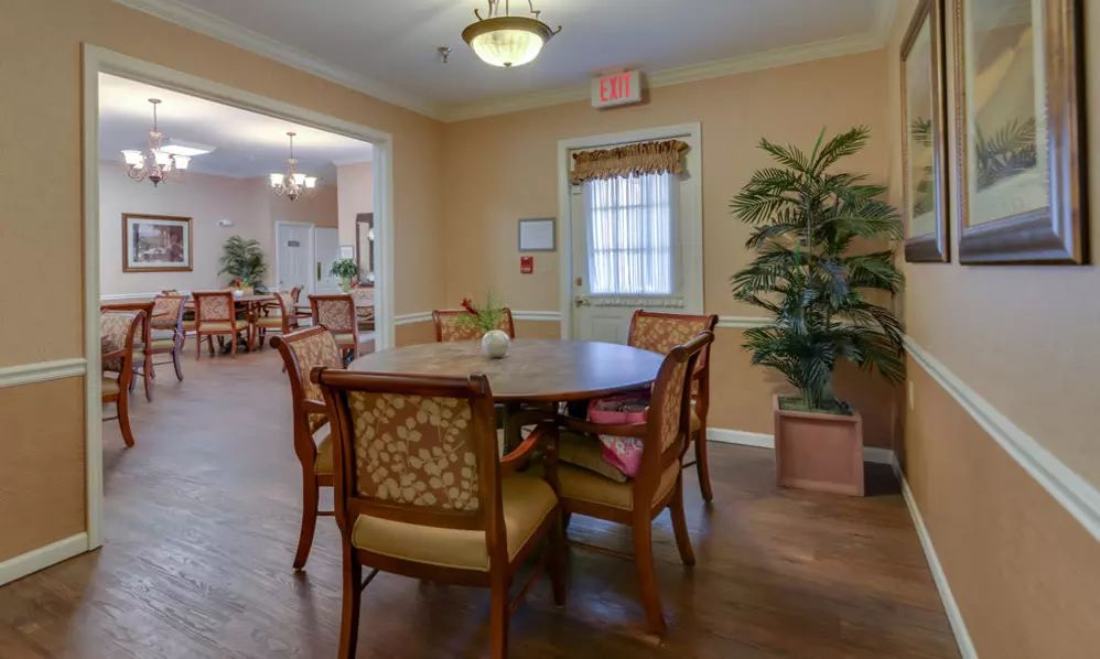A cozy dining area with wooden table and chairs, complemented by warm lighting and indoor plants.