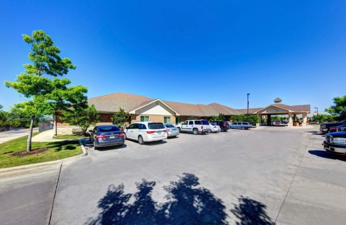 A sunny day with cars parked in front of a building under a clear blue sky.