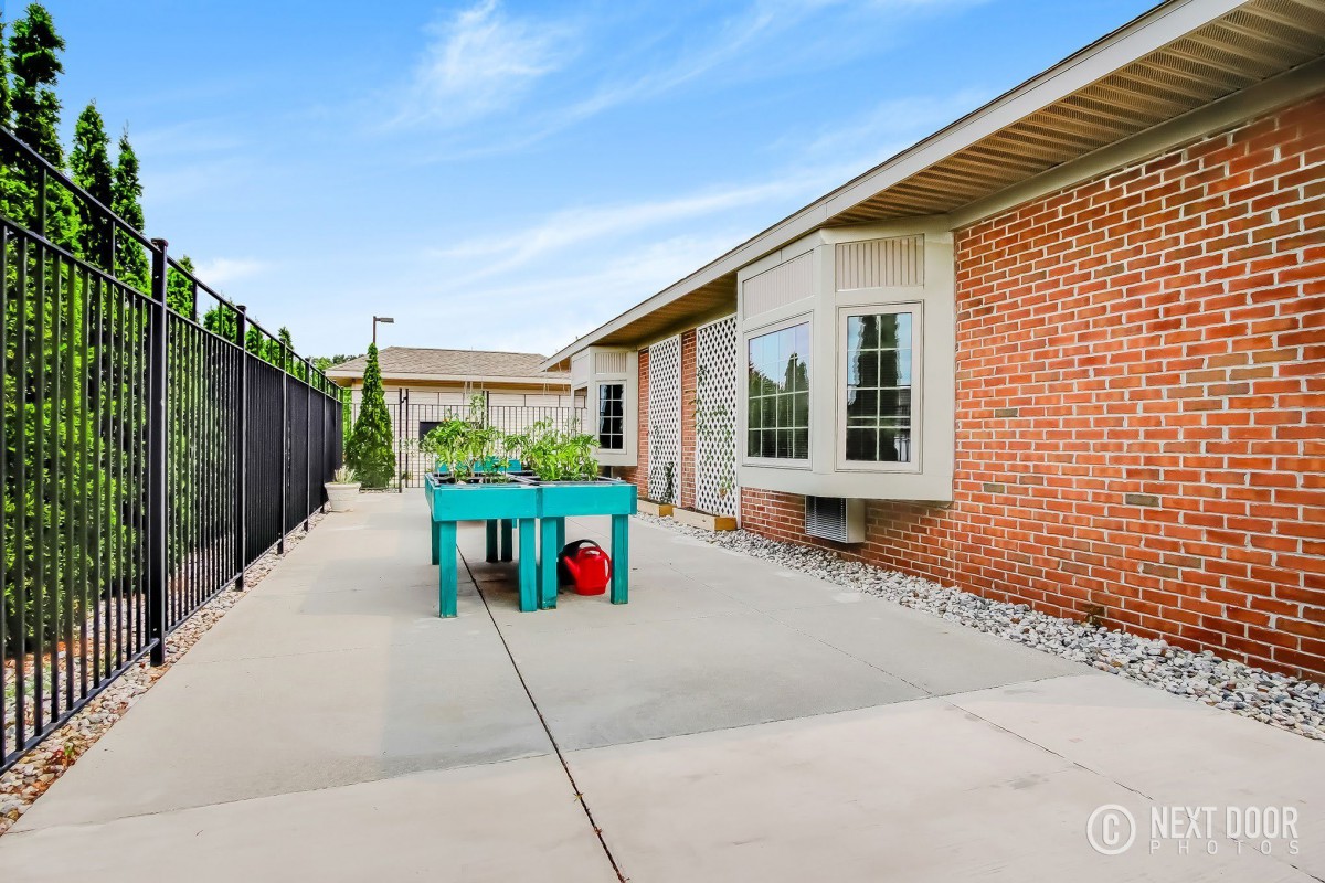 A spacious patio with a garden table and plants next to a brick building.