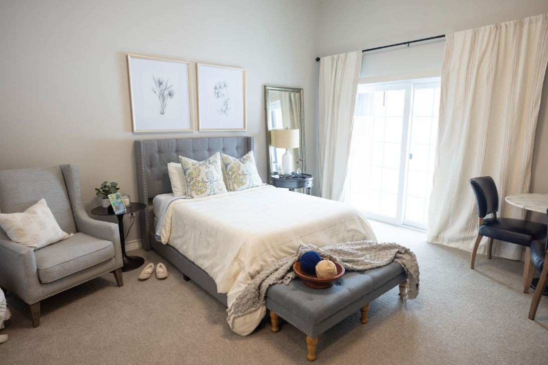 A modern and cozy bedroom with elegant decor, featuring a comfortable bed, stylish artwork, and a large mirror.