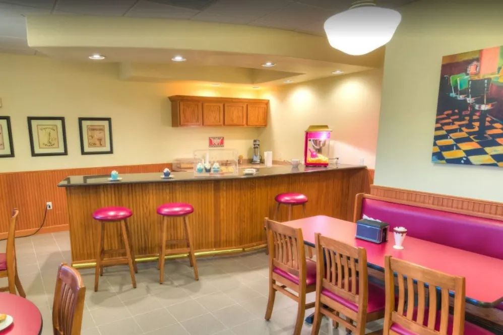 A cozy kitchen dining area with barstools and a wooden table.