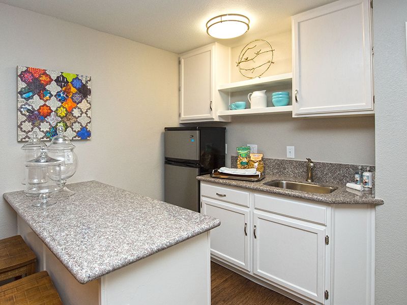 A compact kitchen area featuring white cabinets, a granite countertop, and modern decor.