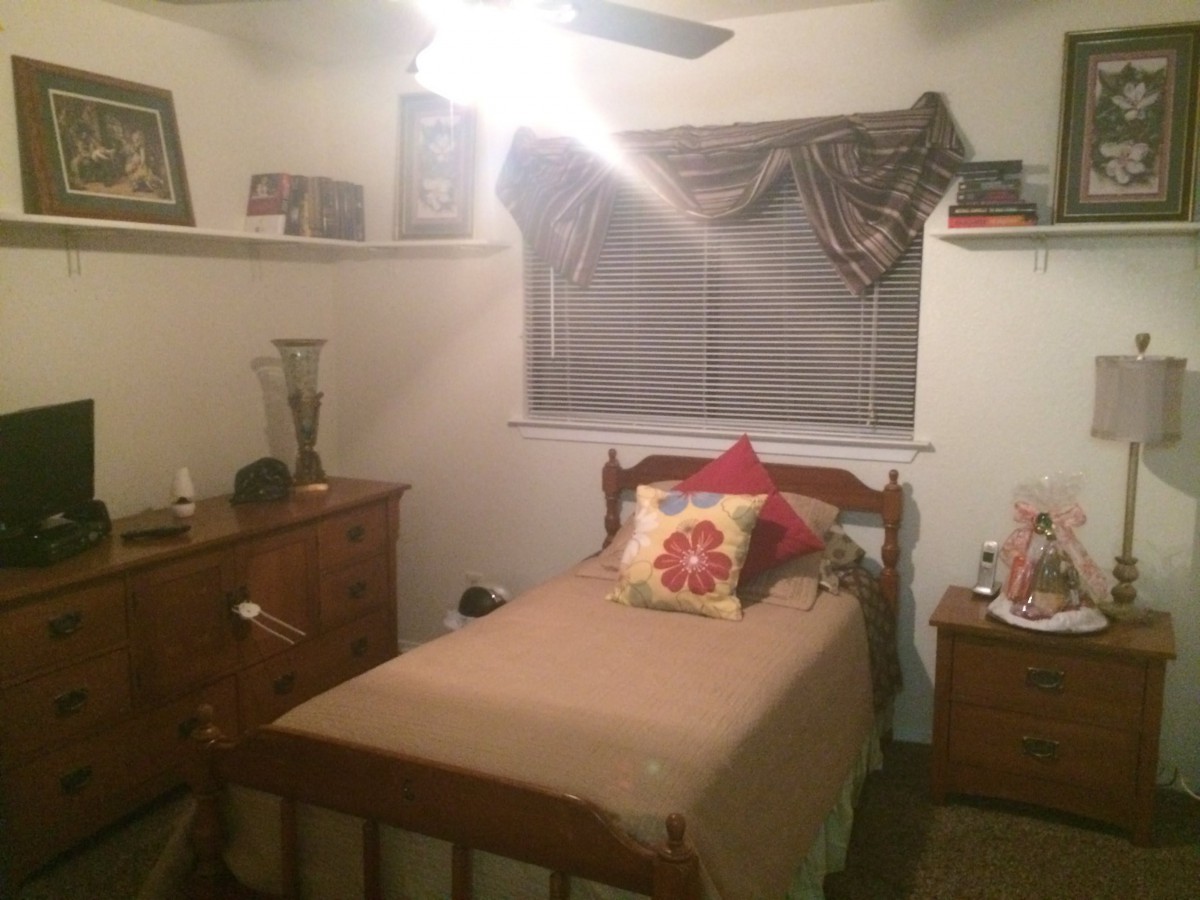 A cozy bedroom with a single bed, wooden furniture, and decorative pillows.