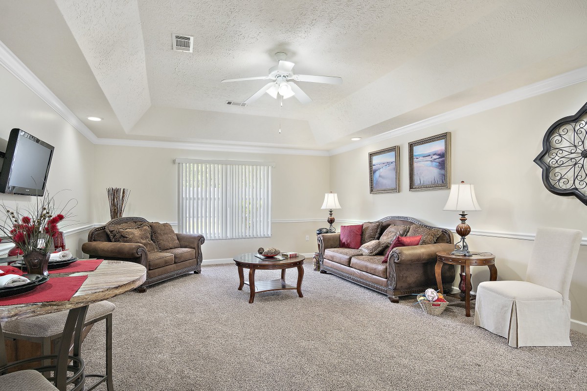 A cozy living room with comfortable sofas, a central coffee table, lamps, and wall art.
