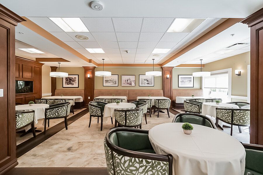 A modern dining area with neatly arranged tables and chairs, featuring elegant lighting and wall art.