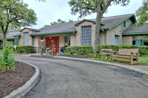 A cozy building with red doors, surrounded by greenery and benches.