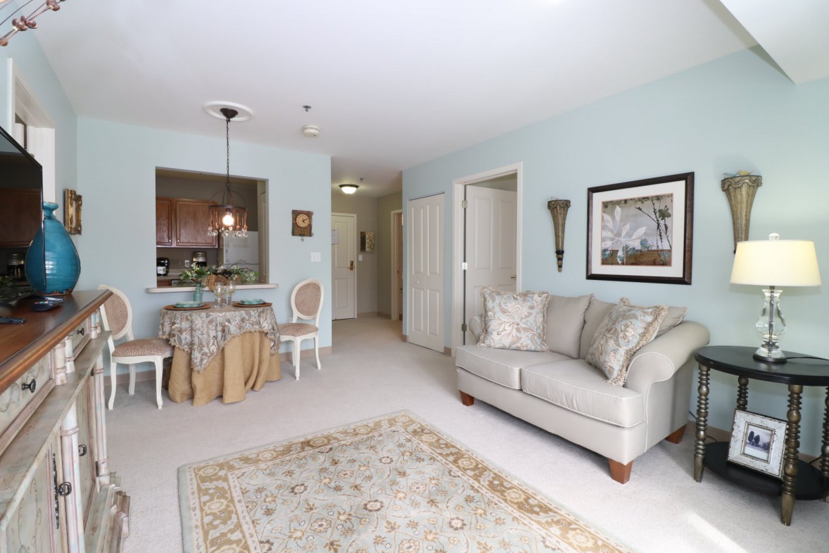 A cozy living room featuring a sofa, a dining area, and elegant artwork on the walls.