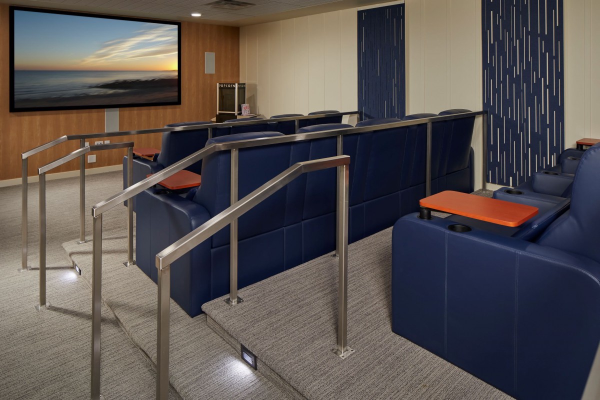 A cozy indoor theater room with tiered seating and a large projector screen.