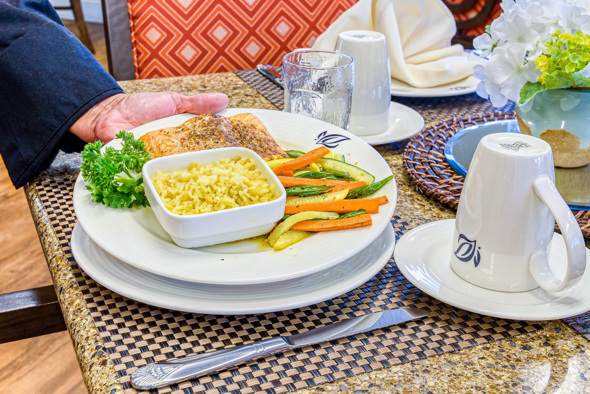 A plate of salmon served with corn and vegetables on a dining table.