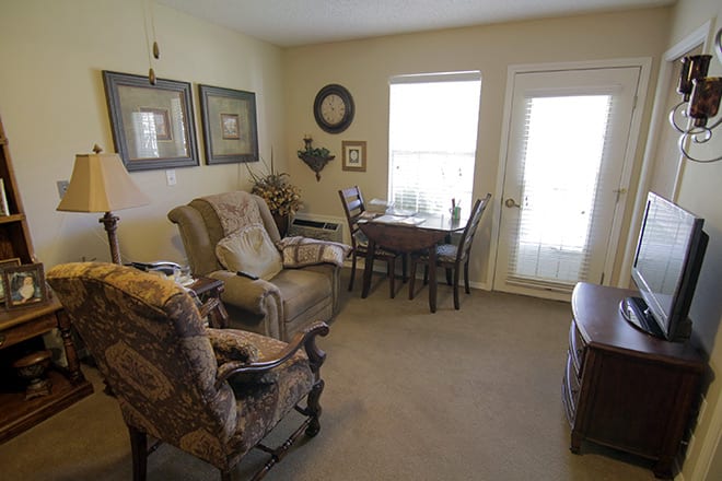 A cozy living room with comfortable chairs and a small dining table near the window.