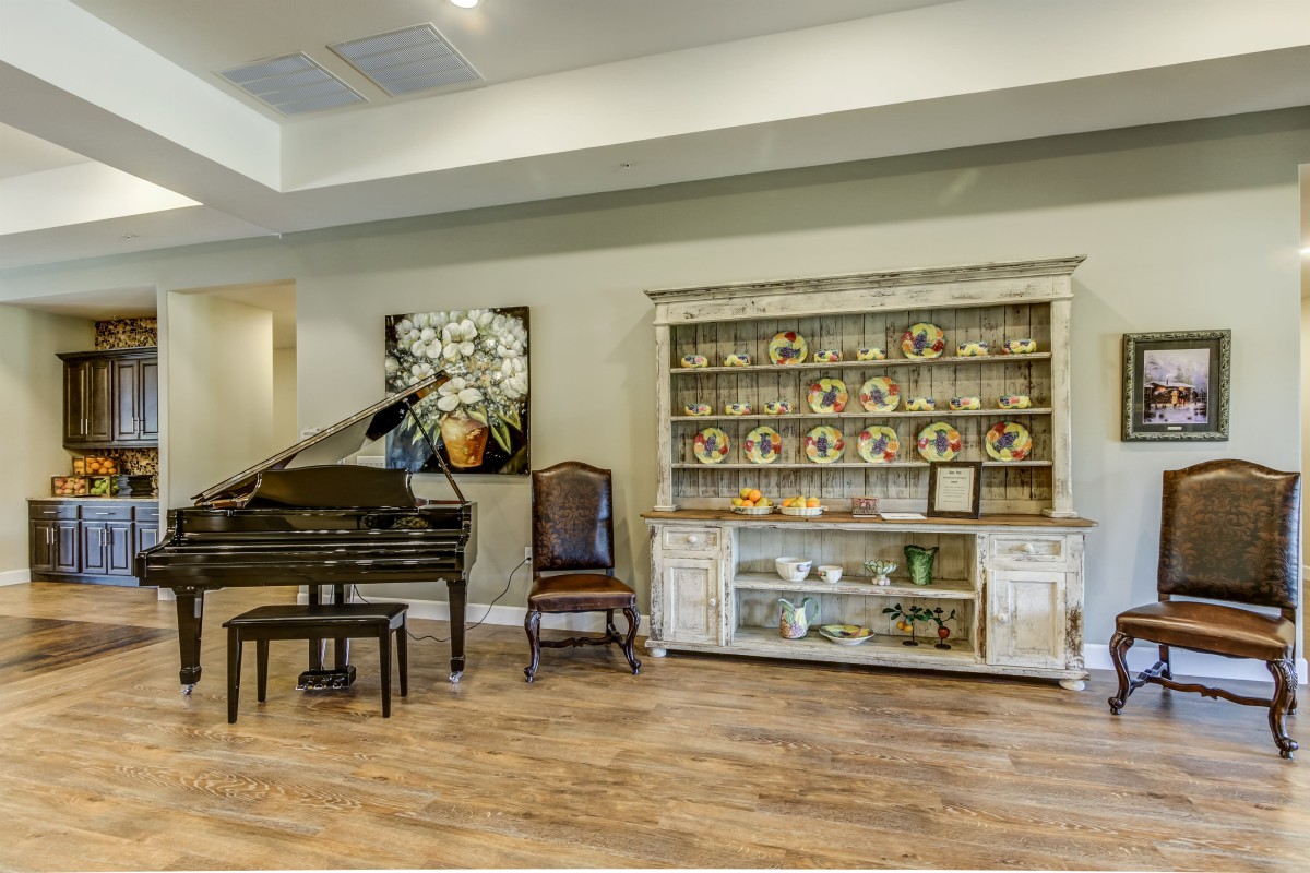 A cozy living room featuring a grand piano, a display cabinet with decorative plates, and elegant artwork.