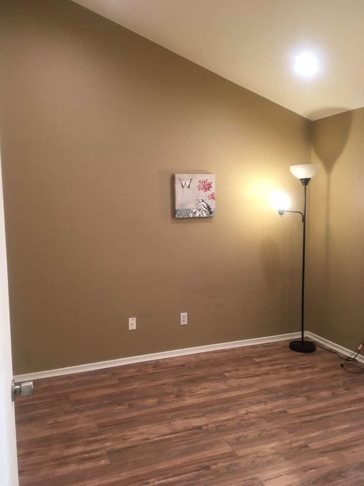 A minimalistic room with a floor lamp, small wall painting, and wooden flooring.