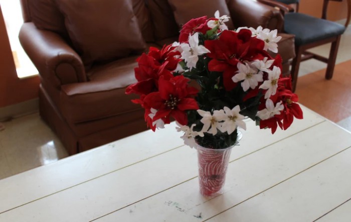 A bouquet of red and white flowers arranged in a vase on a wooden table.
