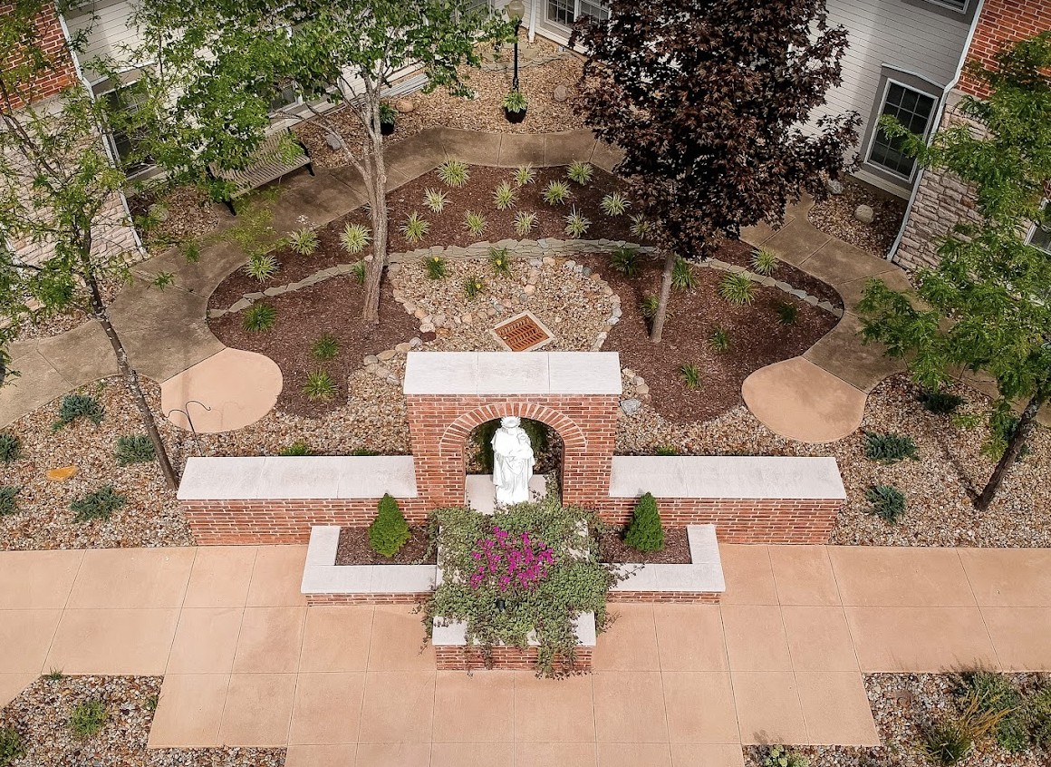 A beautifully landscaped garden with a central statue and surrounding pathways, viewed from above.