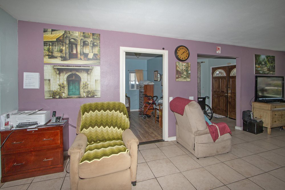 A cozy living room with purple walls, featuring two armchairs and decorative artwork on the walls.