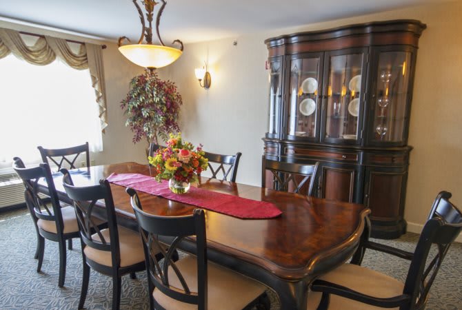 A well-furnished dining room with a wooden table, chairs, and a display cabinet.