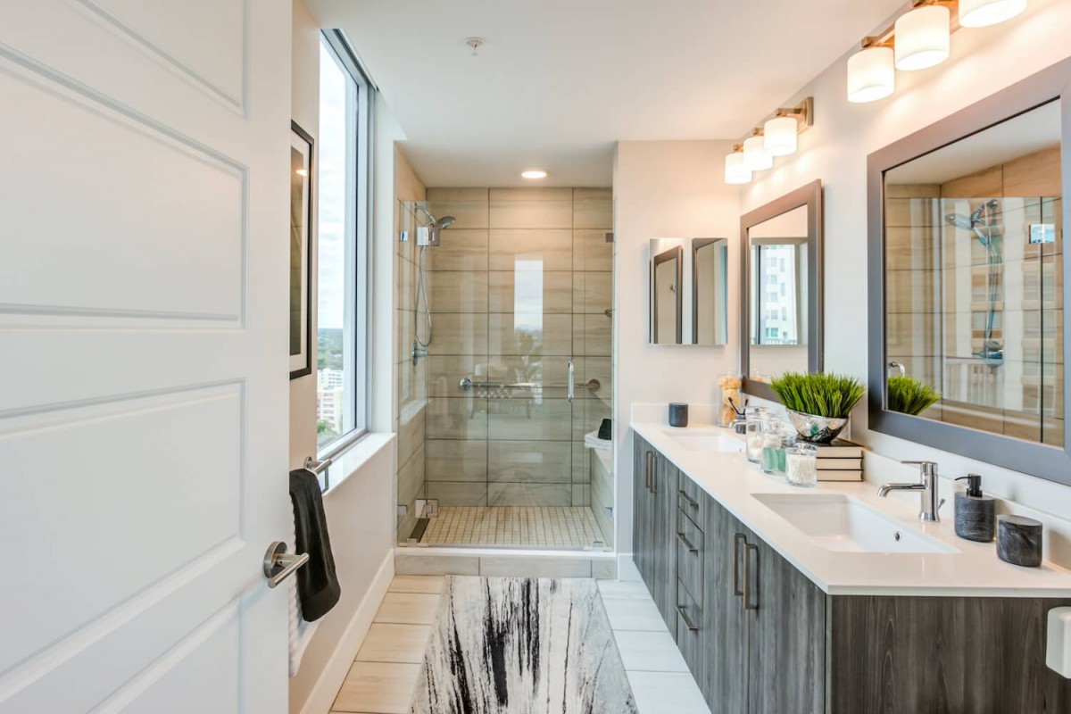 A modern, elegant bathroom featuring a spacious shower, double vanity with mirrors, and ample natural light.