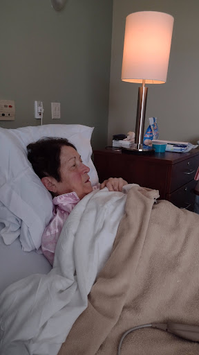 A woman resting in a hospital bed, receiving care.