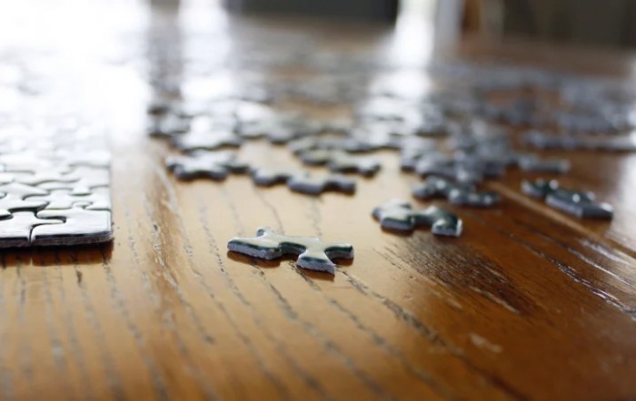 Scattered puzzle pieces on a wooden table.