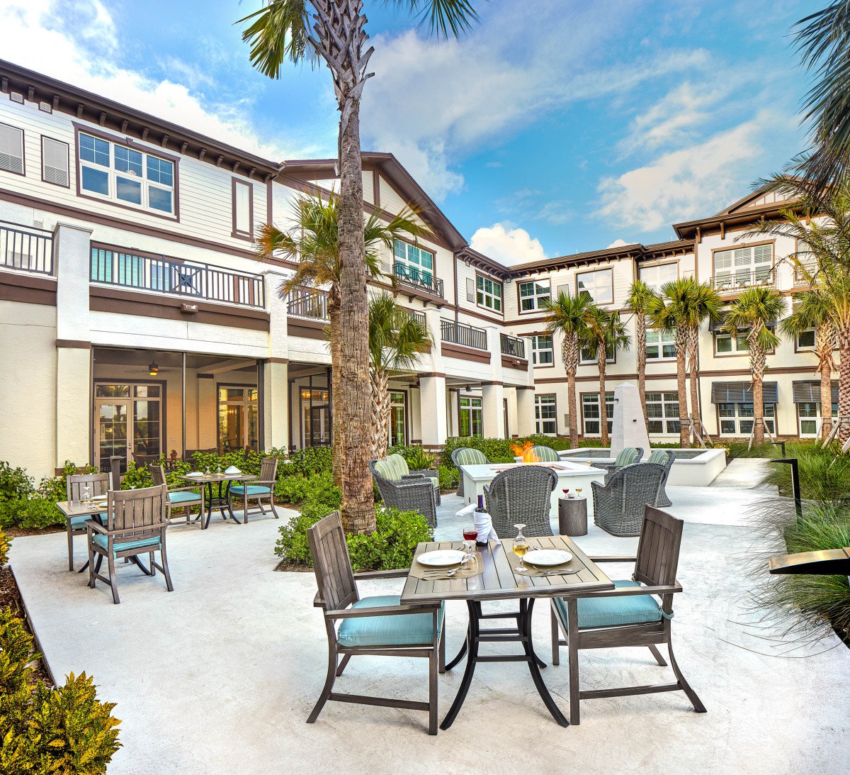 A sunny courtyard with outdoor seating and palm trees.