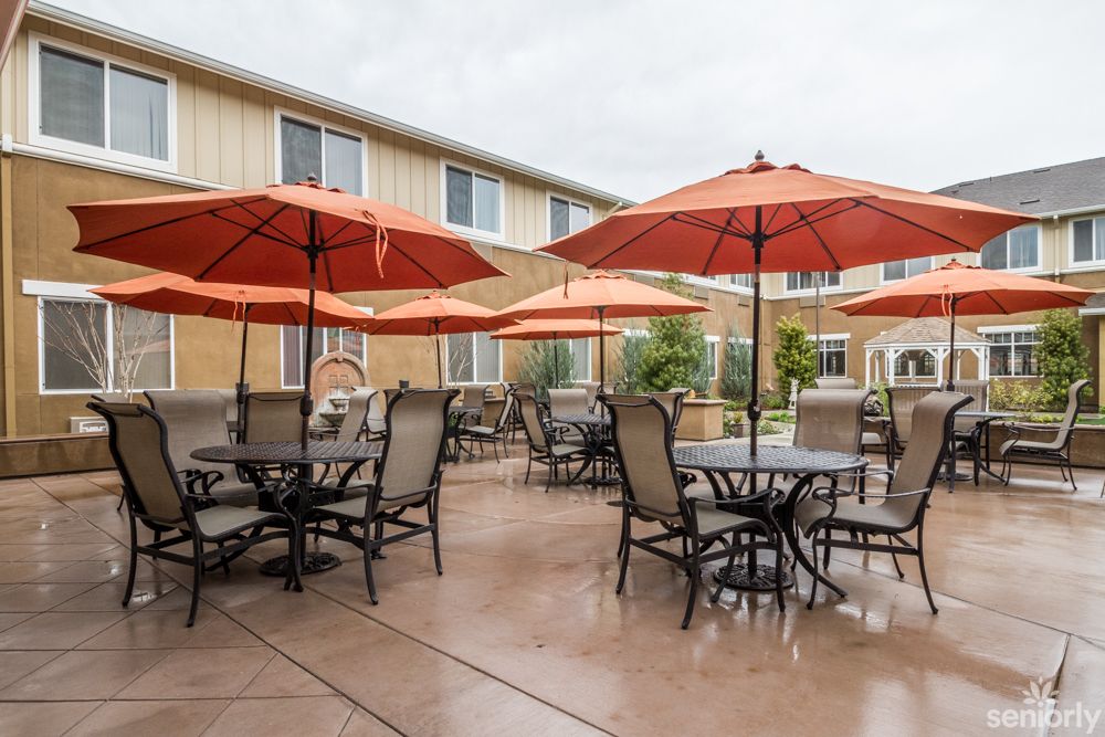 An outdoor patio with tables, chairs, and orange umbrellas.