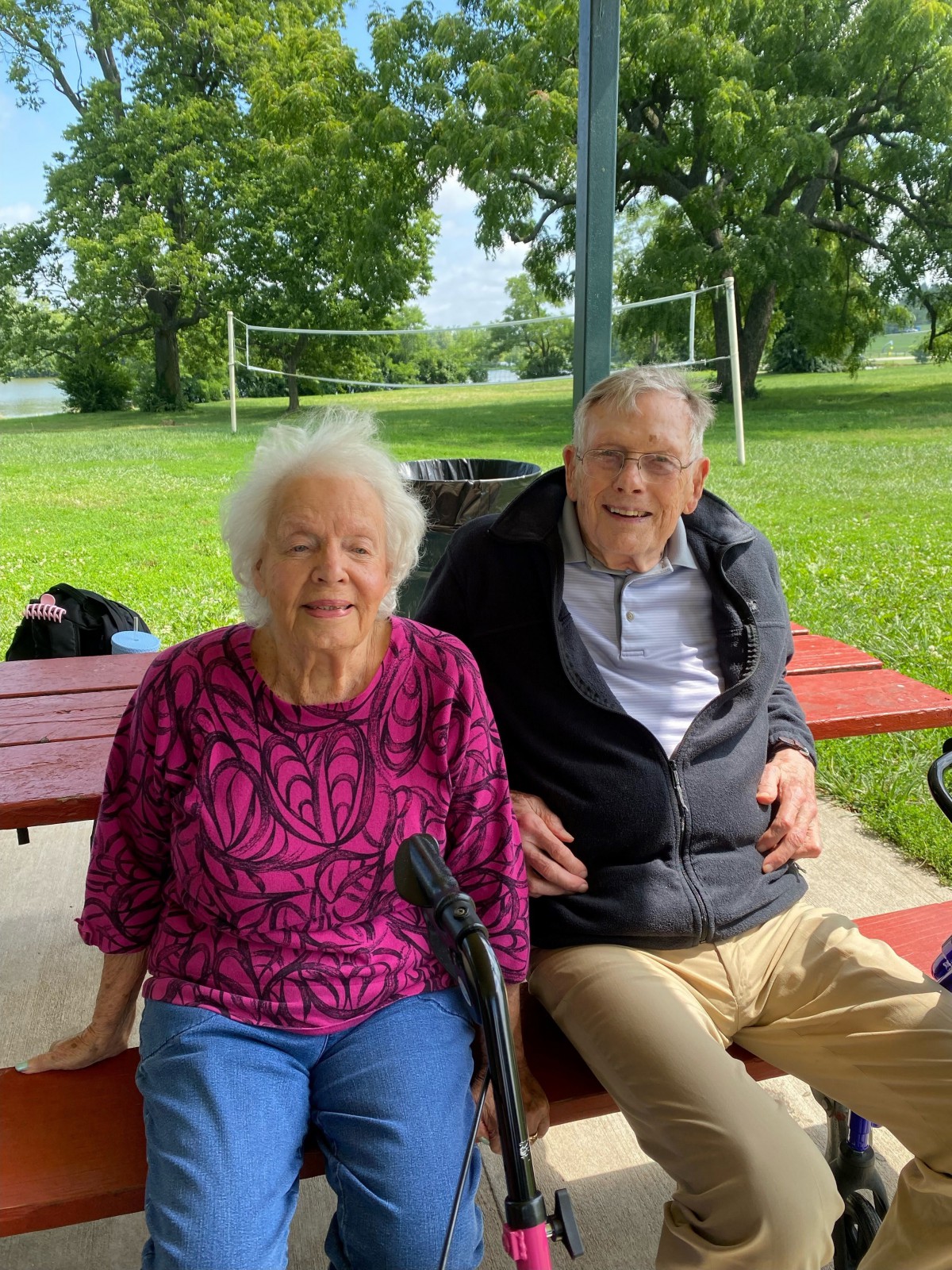 An elderly couple sitting on a bench in a park, enjoying a relaxing day outdoors.
