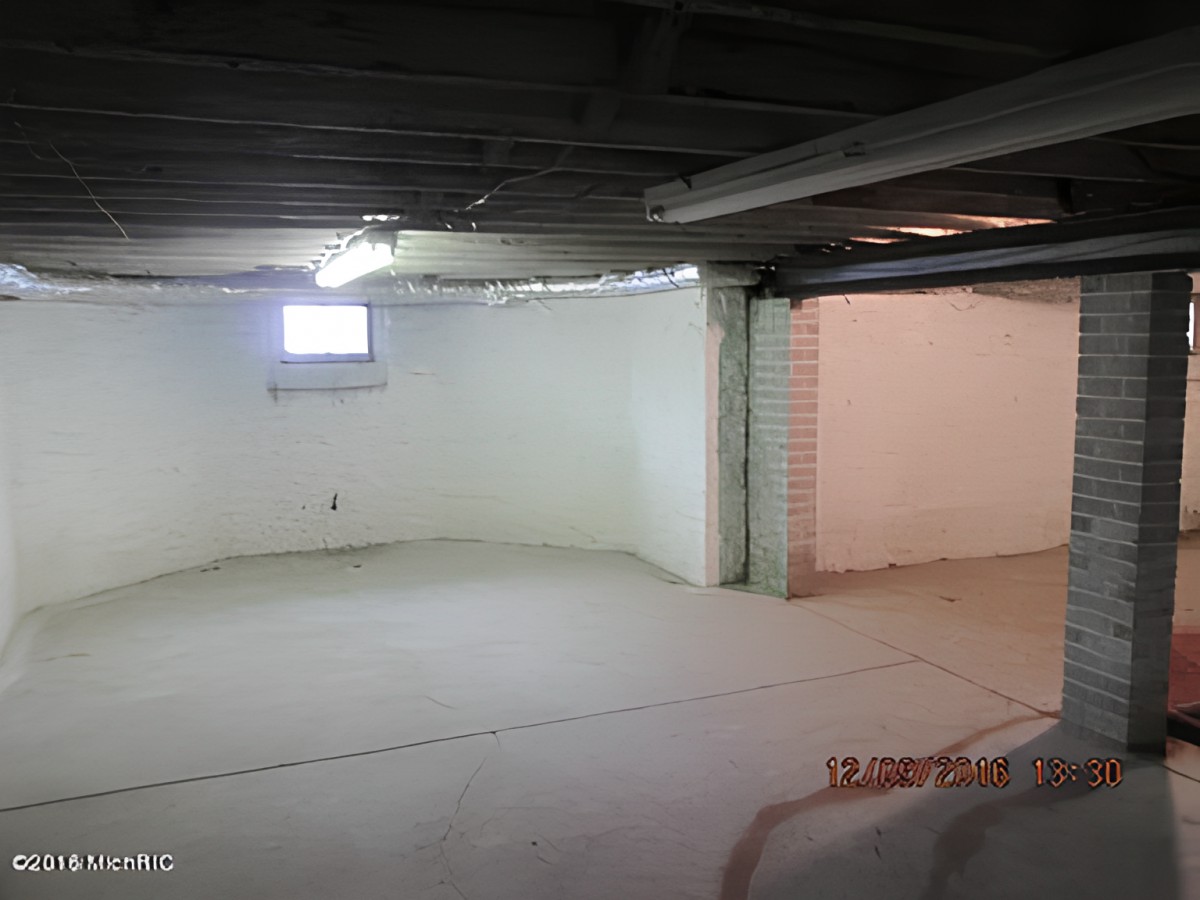 Empty unfinished basement with concrete floor and white walls.