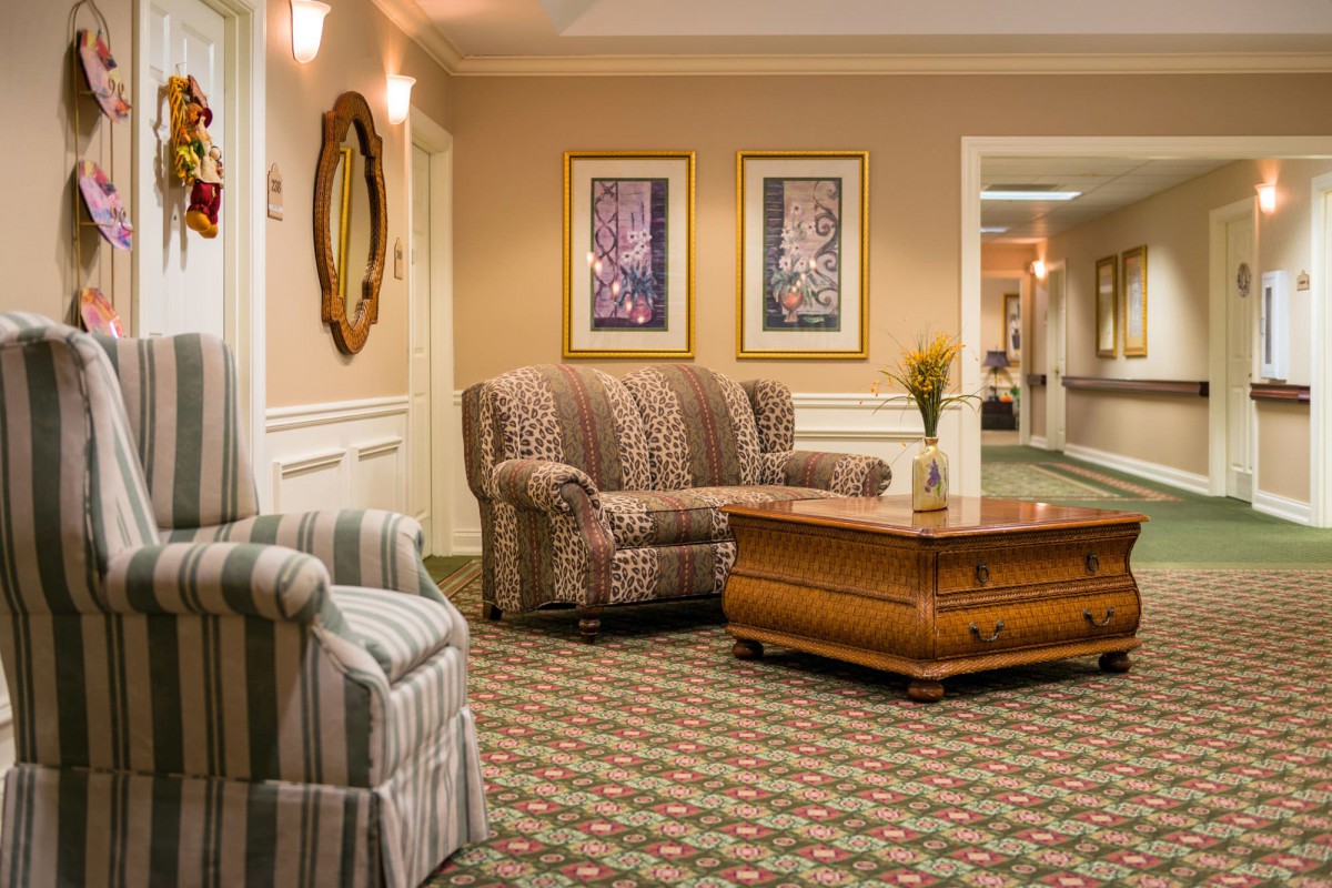 A cozy living room area with a patterned sofa, armchair, and wooden coffee table.