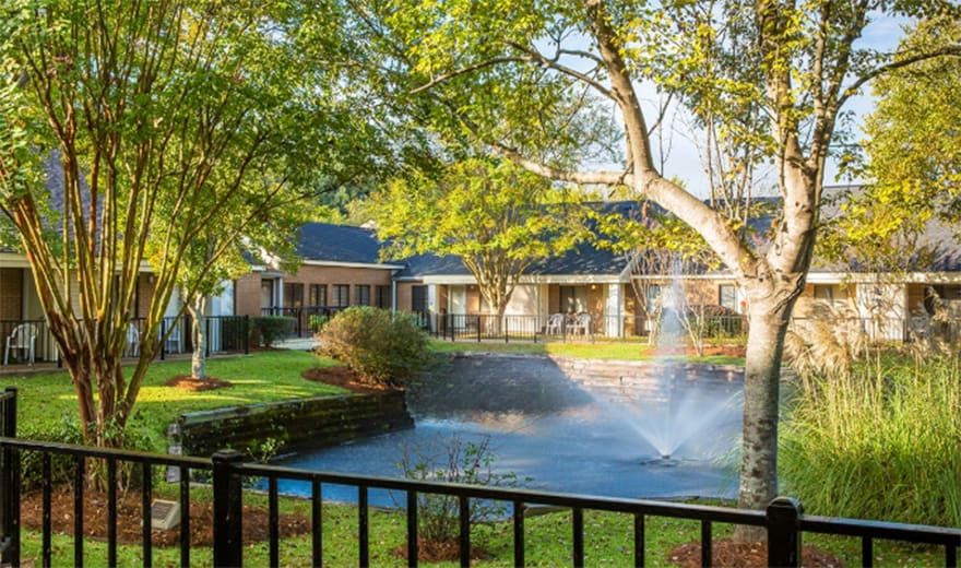 A tranquil garden scene with a fountain and trees, surrounded by buildings.
