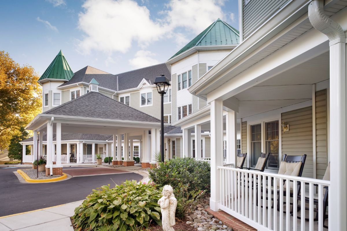 A charming residential building with a porch and lush landscaping.