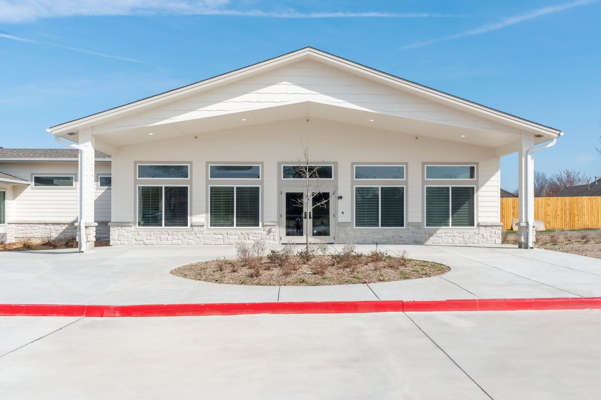 A modern building exterior with large windows and a central entrance under a clear blue sky.