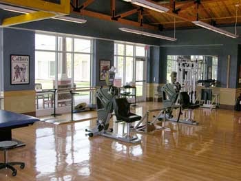 A view of a spacious gym equipped with various exercise machines.