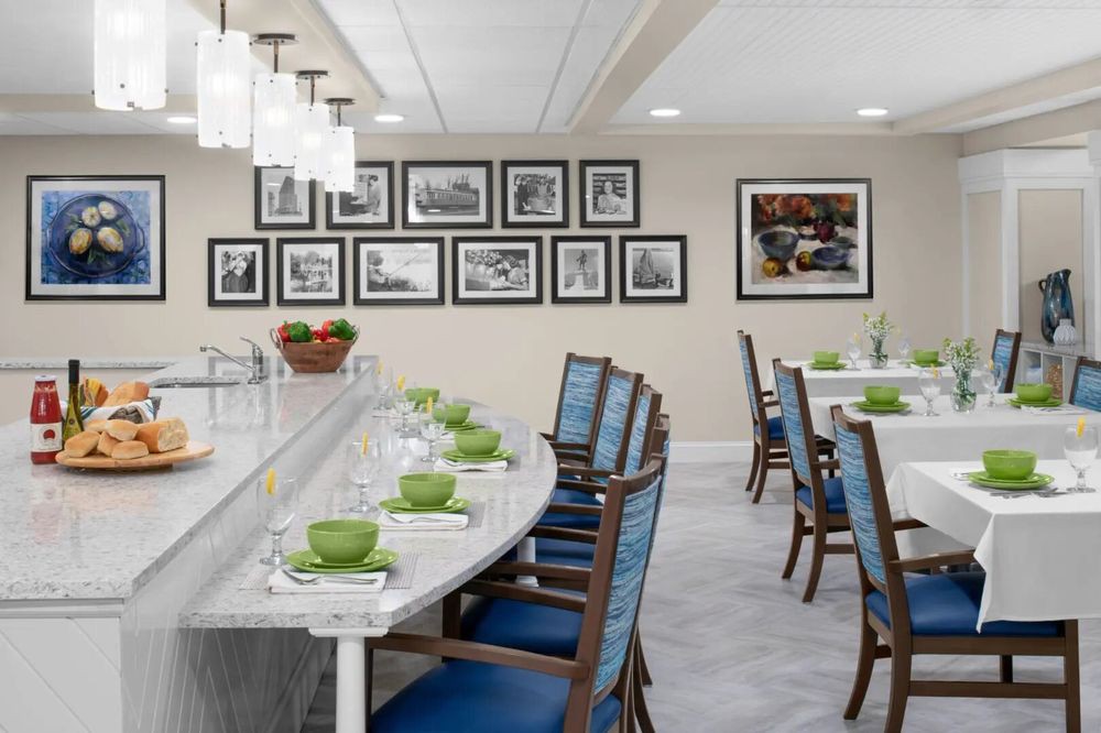 A modern dining area with elegant tables, blue cushioned chairs, and framed pictures on the wall.