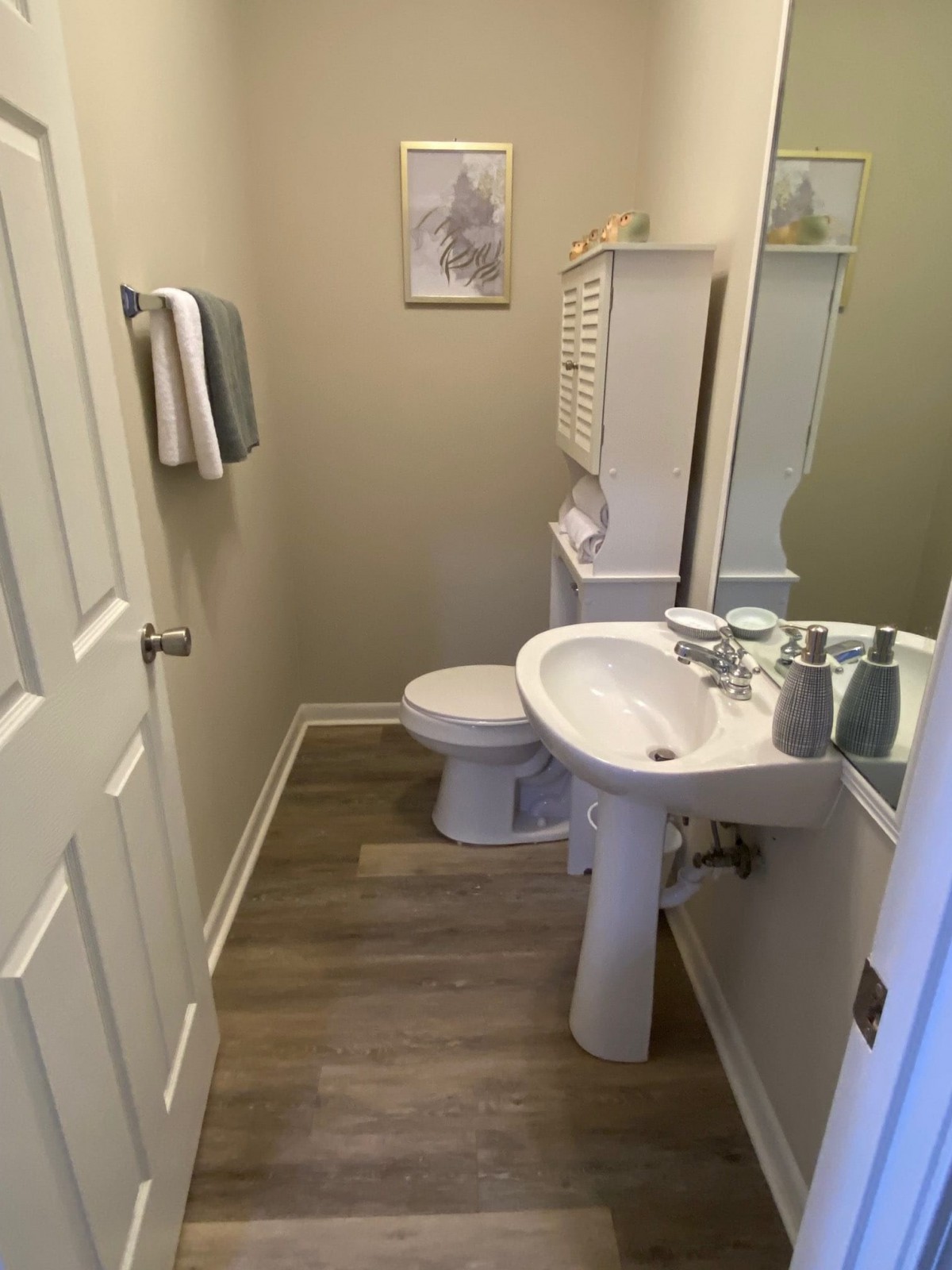 A neatly organized bathroom with a pedestal sink and mirror.