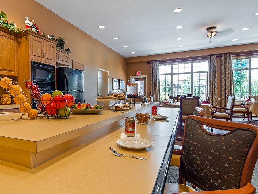 A spacious kitchen and dining area with a long countertop, bar stools, and fruits displayed on the counter.