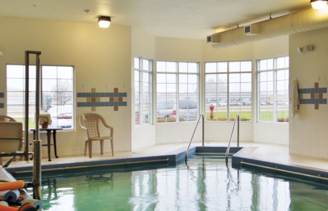 An inviting indoor pool area with large windows and a plastic chair, perfect for relaxation.