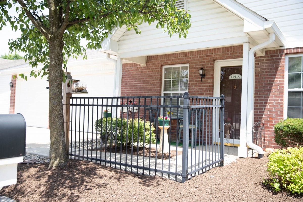 A residential patio with a metal fence and small garden area.