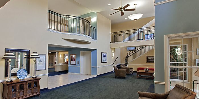 A spacious lobby with modern design, featuring a seating area, stairs, and a ceiling fan.